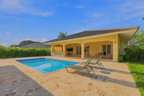 Una casa con piscina, mobiliario de exterior y jardín.