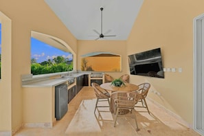 A kitchen with a dining area, a ceiling fan, and a TV mounted on the wall. - 4BR Caribbean Villa in Hispaniola (Sosúa)