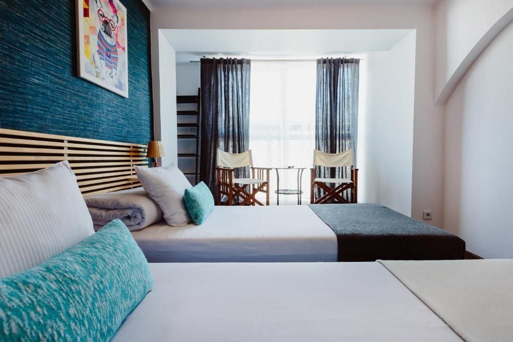 A hotel room with a bed, a desk, and a chair. There is a window with curtains.