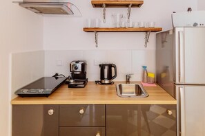 Une petite cuisine équipée d’une machine à café, d’une bouilloire, d’un grille-pain et d’un petit évier.