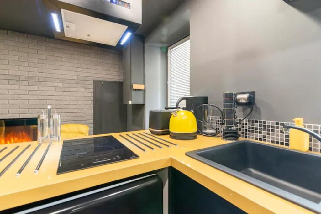 Una cocina moderna con horno empotrado, hervidor, cafetera y pileta.