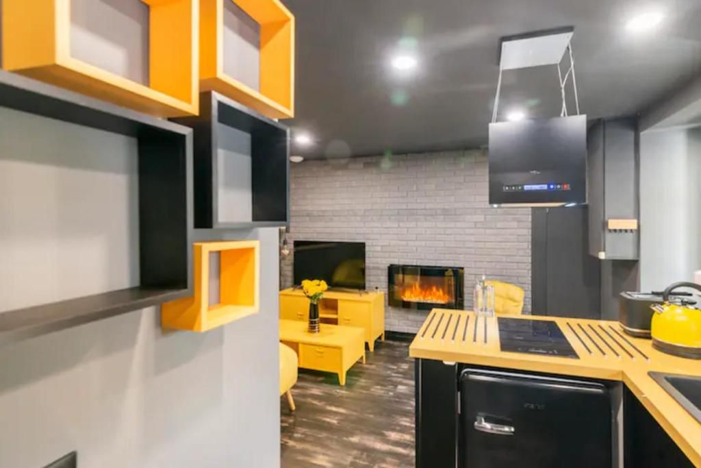 Una sala de estar moderna con chimenea, muebles amarillos y un mueble de entretenimiento negro.