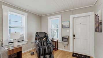 Une pièce équipée d’un fauteuil de massage, d’une petite table avec une lampe, d’un radiateur et d’une porte avec un paillasson.