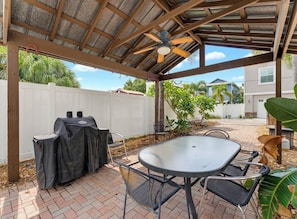 Un patio couvert avec un barbecue, une table et des chaises.
