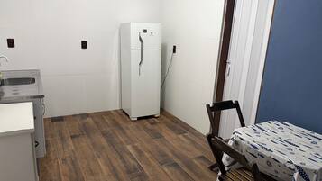 Cozinha compacta com geladeira, pia e mesa com toalha de mesa estampada.