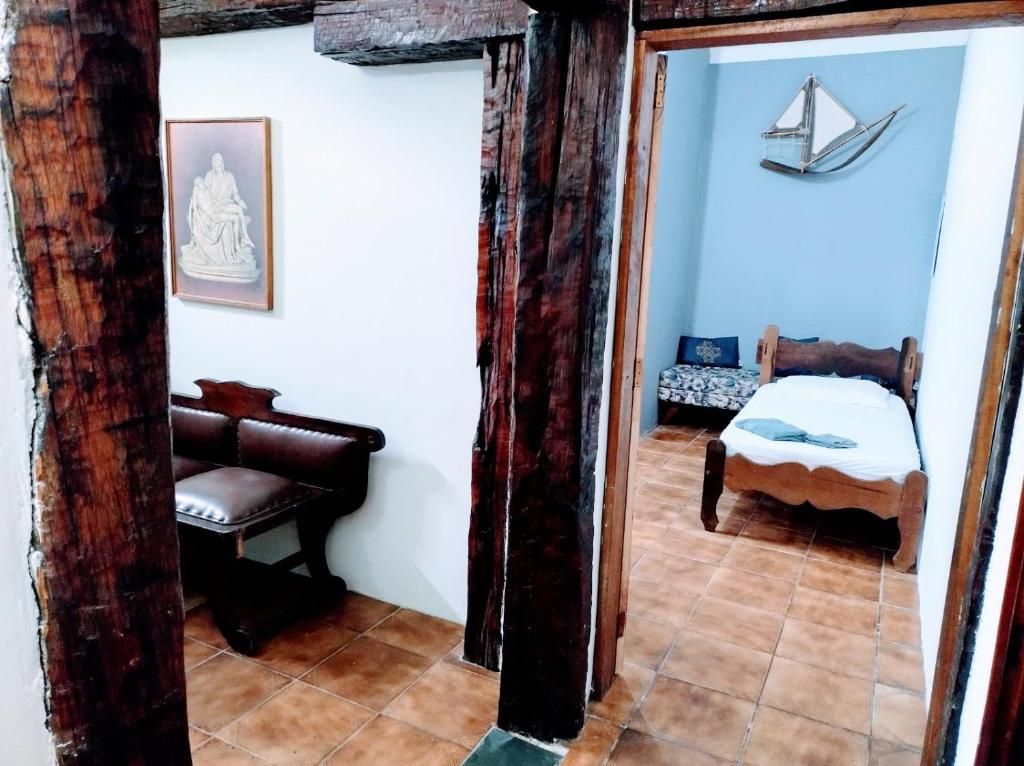 A room with a bed, a bench, and a wall-mounted sculpture.