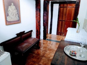 A room with a brown leather sofa, a dining table with a tray of snacks and glasses, and a statue on the wall. - Pousada Villavera (Caraguatatuba)