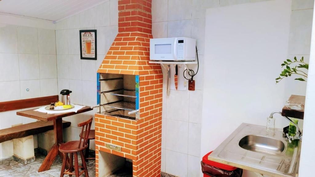 A kitchen with a brick oven, a microwave, a sink, and a dining area with chairs.