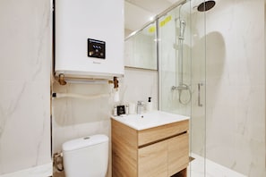 A modern bathroom with a toilet, a shower with a glass enclosure, and a vanity with a mirror. - Amazing Studio 2P- Arc de Triomphe-champs Elyse (Paris)