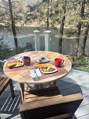 A wooden deck with a round table set for breakfast, overlooking a body of water and trees. - The Bear Lair - timber frame lake retreat in Wildwood’s private 740ac. community (Tolland)
