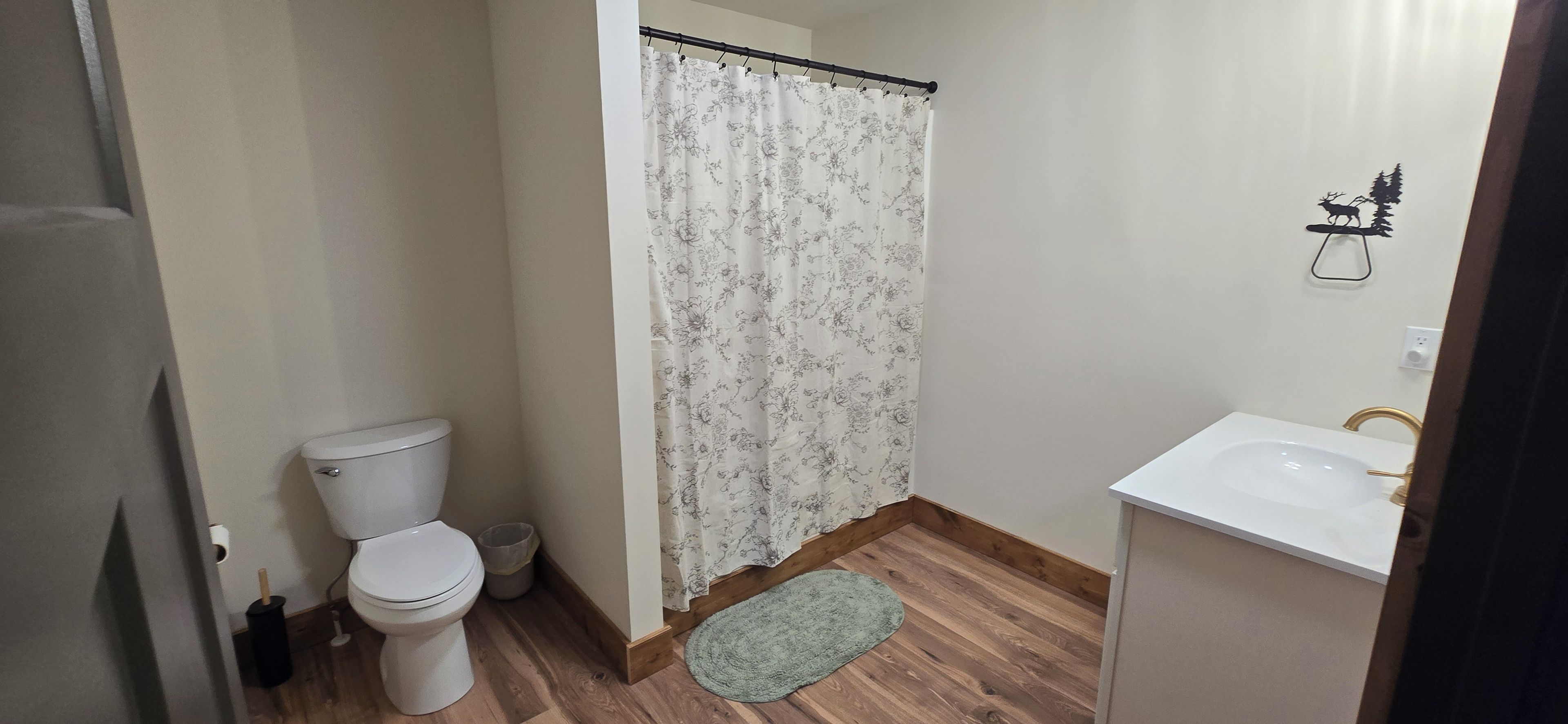 Une salle de bain avec des toilettes, un rideau de douche, un lavabo et un petit tapis.