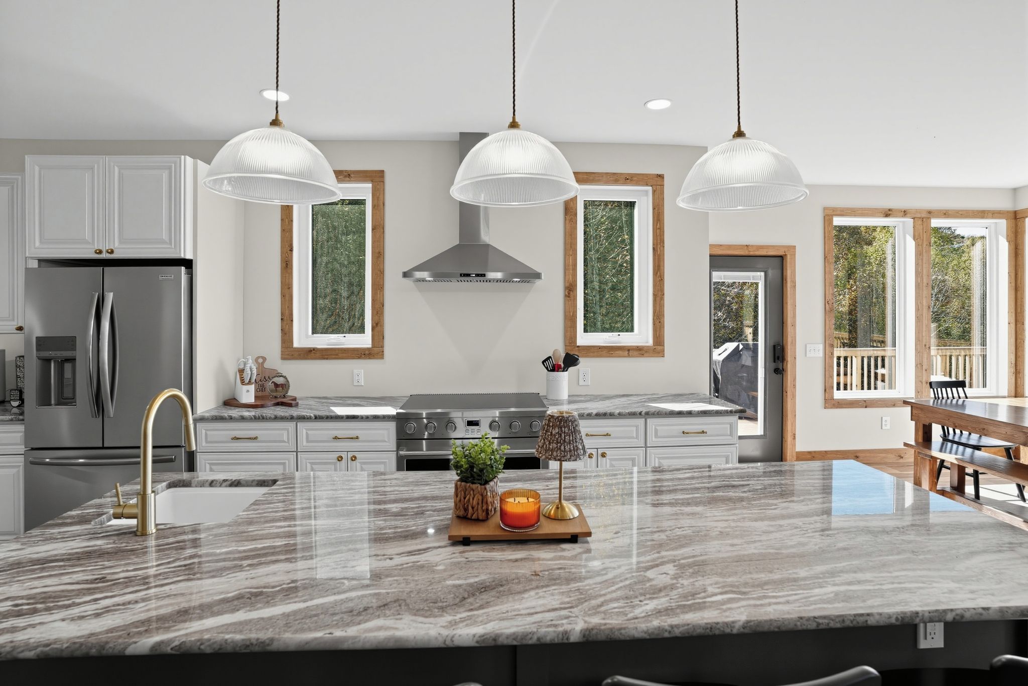 Una cocina moderna con una isla grande, electrodomésticos de acero inoxidable e iluminación colgante.