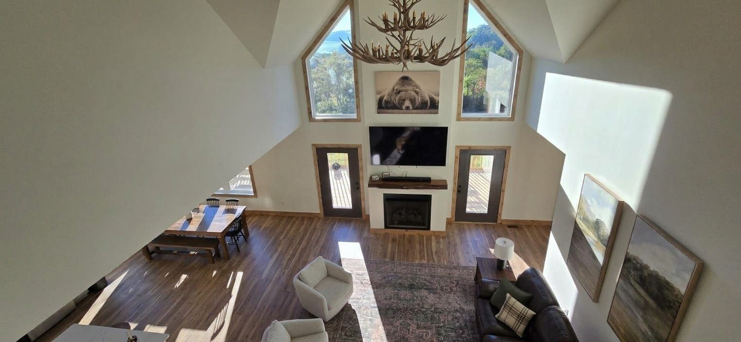 Un amplio salón con techo alto, chimenea, televisor y mesa de comedor.