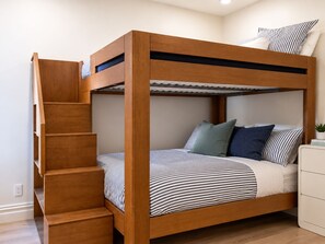 Una cama litera con estructura de madera, una escalera y una mesita de noche con una planta.