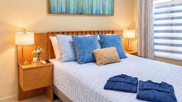 A bedroom with a bed, nightstands, a ceiling fan, an air conditioning unit, a window with curtains, and a wall-mounted painting.