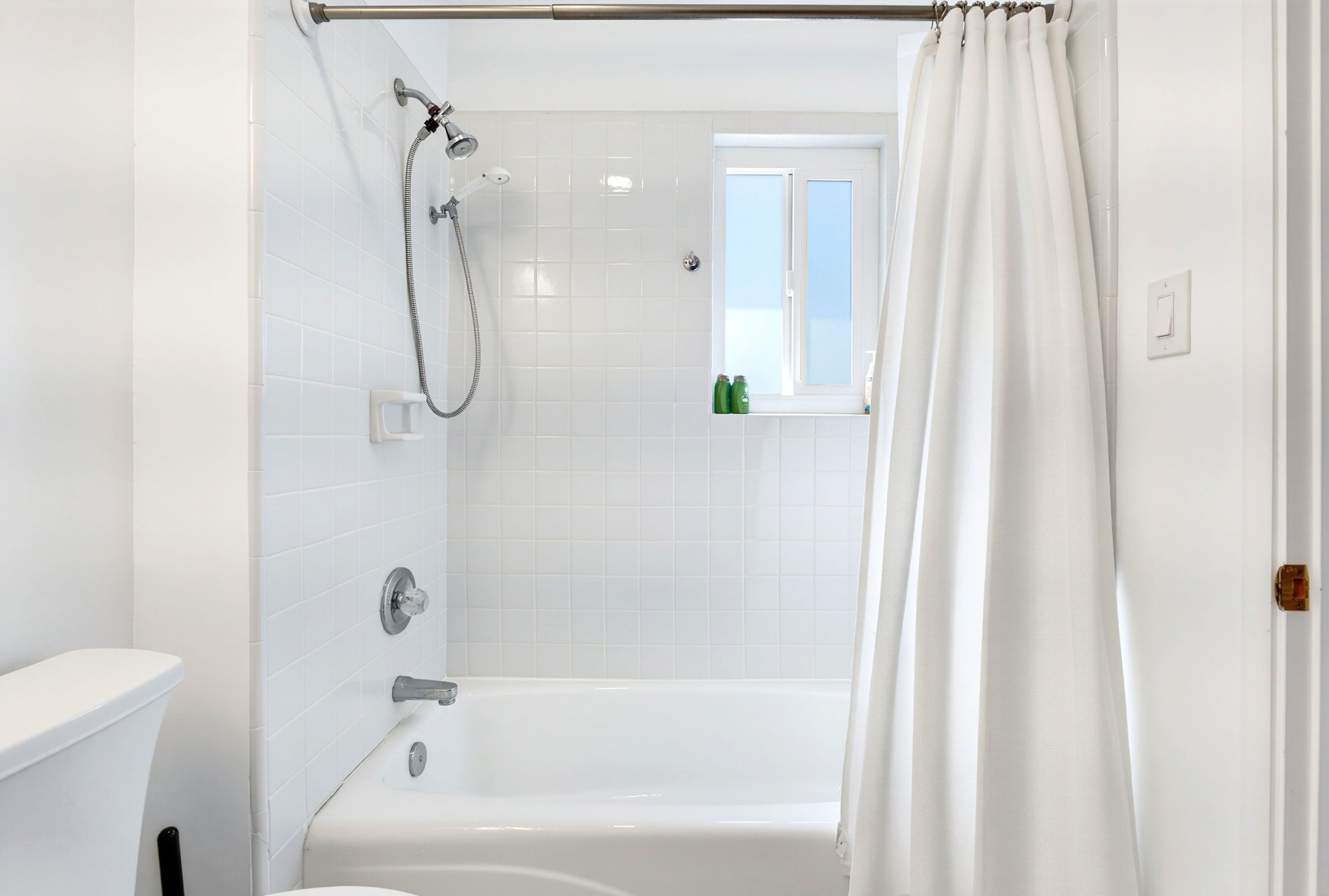 A bathroom with a bathtub, shower, and toilet.