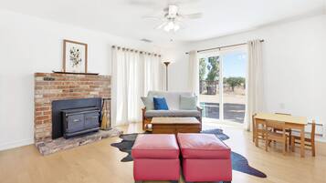 A living room with a fireplace, a sofa, a table, and a view through a sliding glass door.