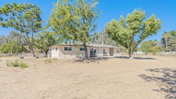 A single-story building with a flat roof, surrounded by dry grass and trees.