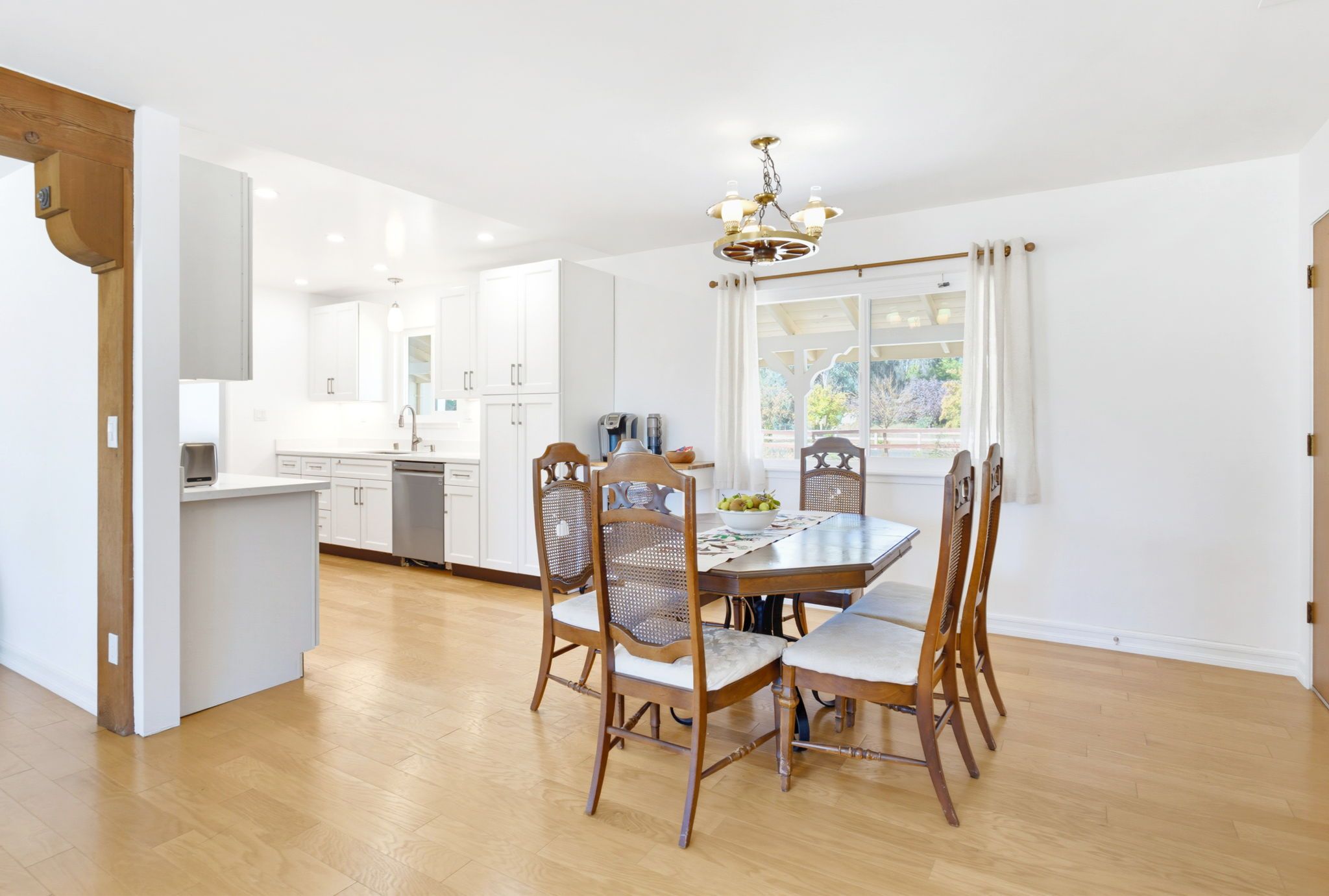 Een moderne keuken met witte kasten, een eettafel met stoelen en een kroonluchter.