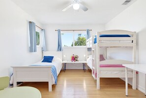 A child's bedroom with bunk beds, a desk, and a window.
