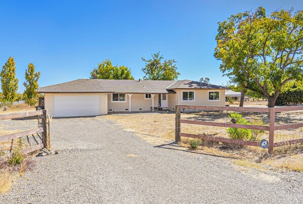 A two-story house with a garage, a covered patio, and a fenced driveway.
