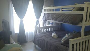 A bunk bed room with a window, curtains, and a plush toy on a wooden nightstand.