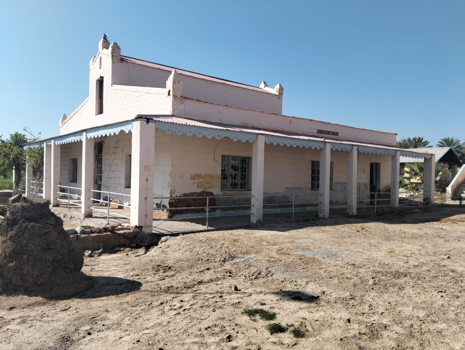 A single-story building with a flat roof, a porch with a railing, and a small staircase leading to the entrance.