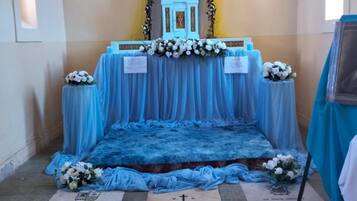 A chapel interior with a blue altar, floral decorations, and religious statues.