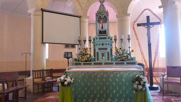 A church interior with a central altar, pews, and a cross.