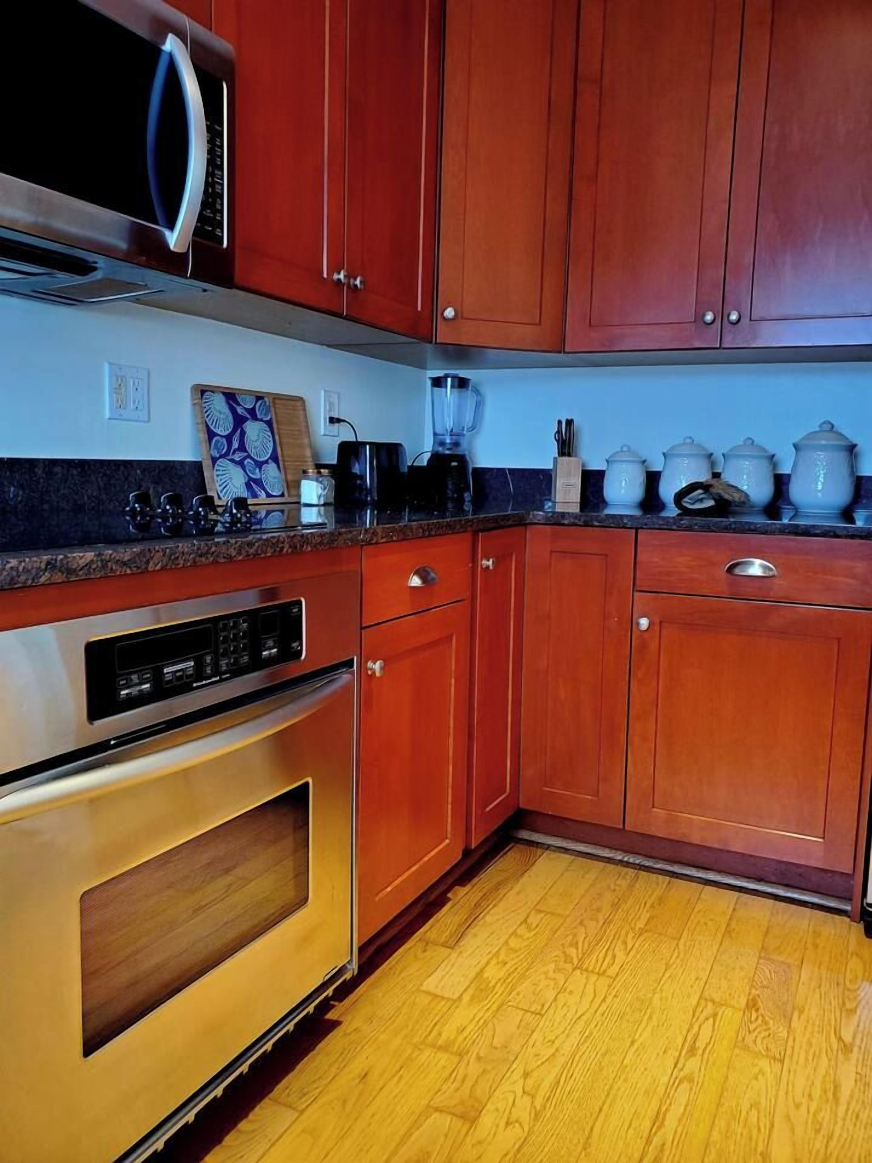 A kitchen with wooden cabinets, a built-in oven, and a microwave.