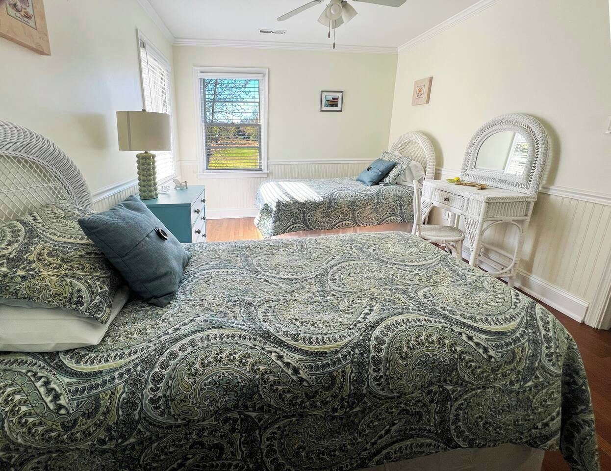 Une chambre avec deux lits, une commode et une fenêtre donnant sur un beau paysage.