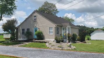 A single-story house with a front porch, a blue door, and a small garden area.