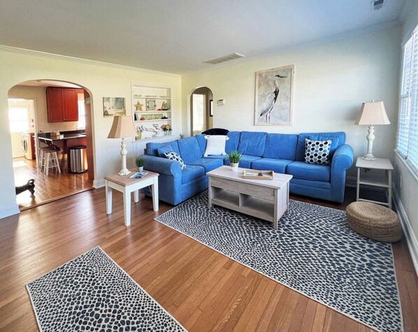 A living room with a blue sofa, a coffee table, and a patterned rug.