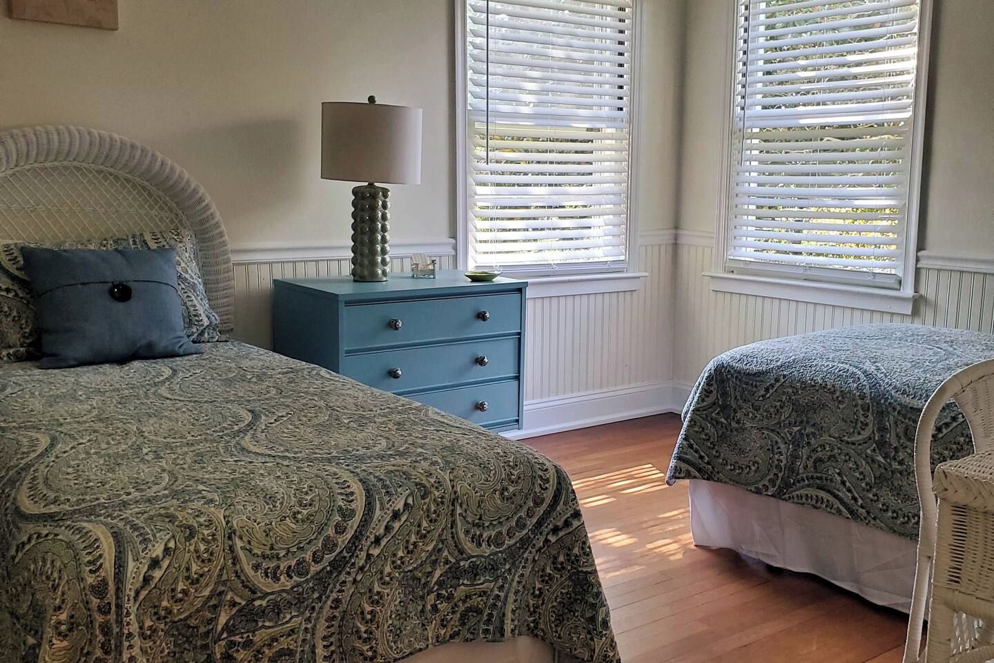 Une chambre avec deux lits, une commode et une lampe.