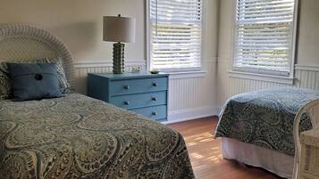 Une chambre avec deux lits, une commode et une lampe.