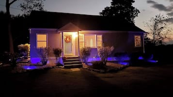 A house with a front porch, a door with a wreath, and a small step leading up to the entrance.