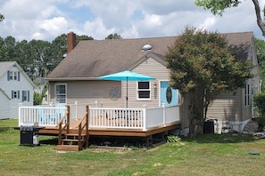 A house with a deck, a covered outdoor area, and a tree.