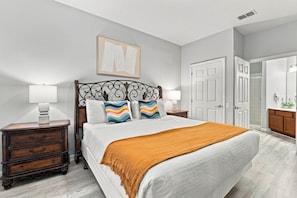 A bedroom with a bed, two nightstands, a dresser, a door, and a framed picture on the wall. - 3BR at Vista Cay, where Comfort meets Convenience (Orlando)
