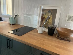 A kitchen with a wooden countertop, a kettle, a tablet, a knife holder, and a bowl. - PAOLO'S CHARMING APARTMENT (Puteaux)