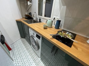 A compact kitchen with a dishwasher, a sink, a kettle, and a pan on the counter. - PAOLO'S CHARMING APARTMENT (Puteaux)