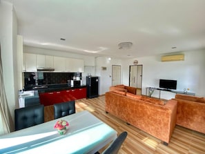 Un espai habitable compacte amb una cuineta, zona de dinar i zona de seients amb un sofà.