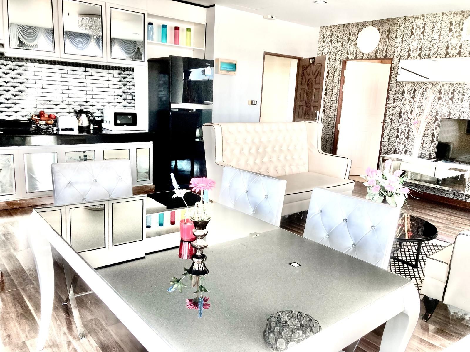 A modern living room with a sofa, a dining table, and a kitchen area with a refrigerator.