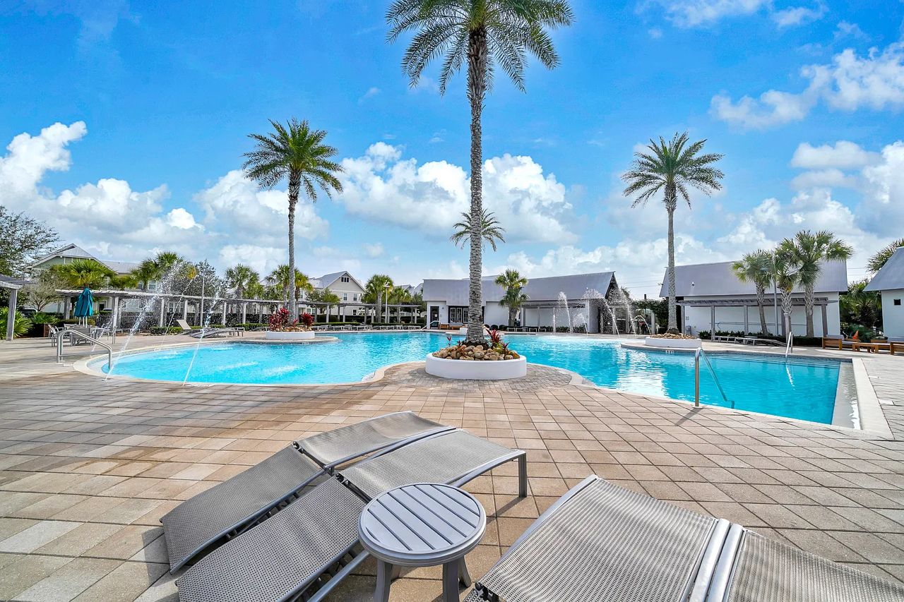 A pool area with lounge chairs and palm trees.