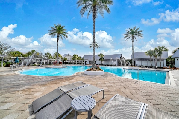 A pool area with lounge chairs and palm trees.