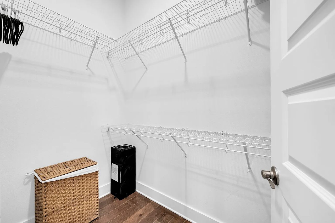 A laundry room with metal drying racks, a trash bin, and a wicker basket.