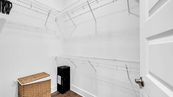 A laundry room with metal drying racks, a trash bin, and a wicker basket.
