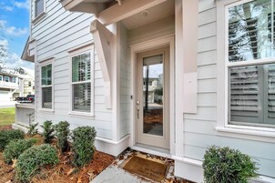 Una casa residencial con puerta principal, dos ventanas y un pequeño porche.