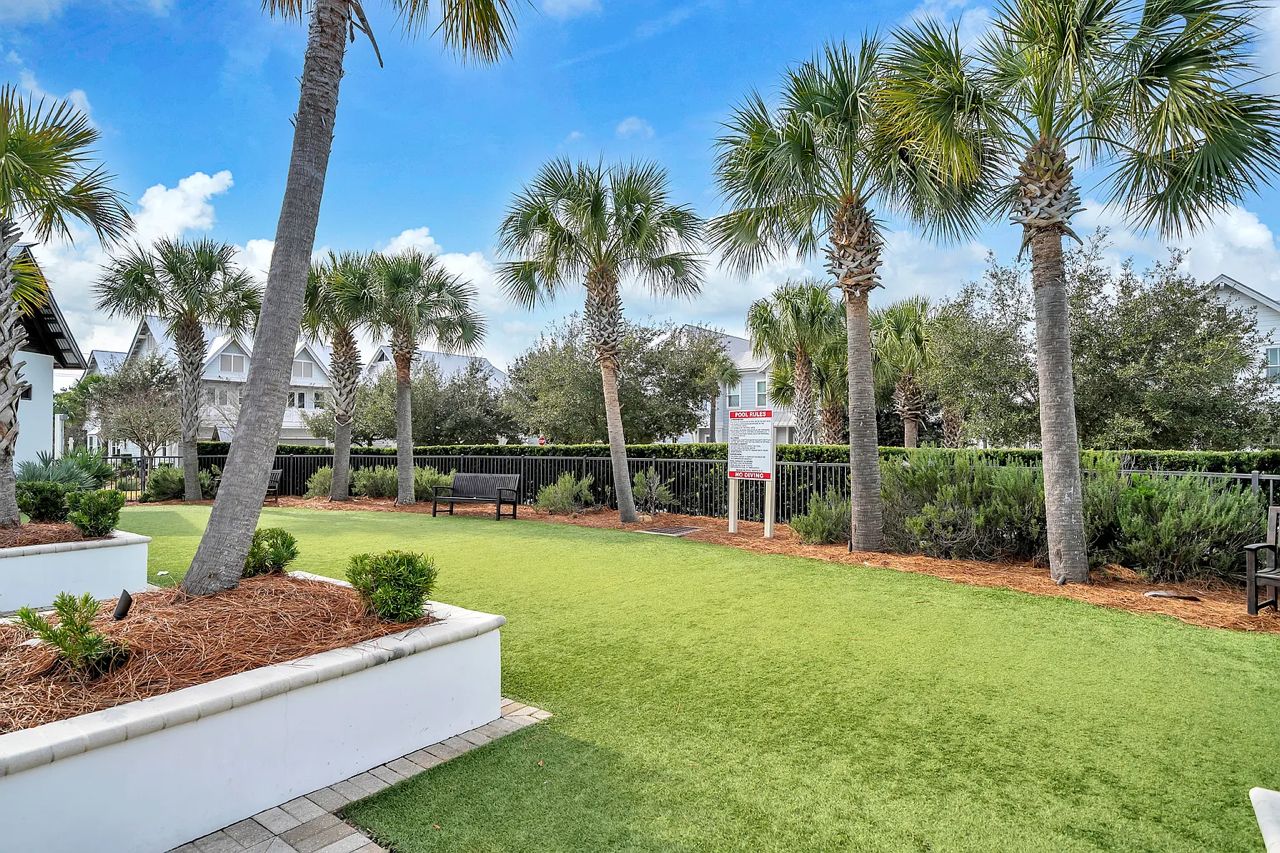 A well-maintained outdoor area with palm trees, a grassy lawn, and a bench.
