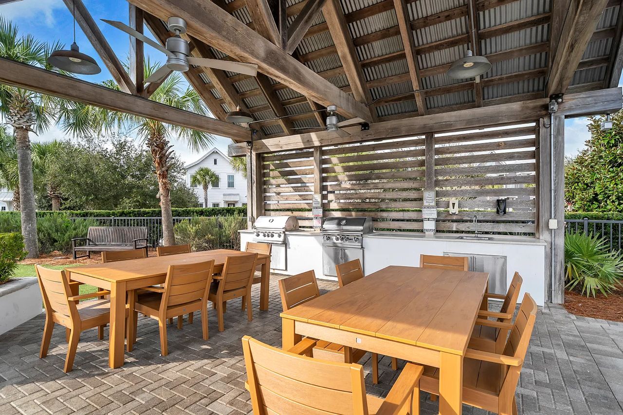 Un patio exterior con mesa y sillas de madera, una parrilla y zona de barbacoa.
