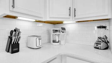 A kitchen with white cabinets, a toaster, a coffee maker, and a blender on the countertop.